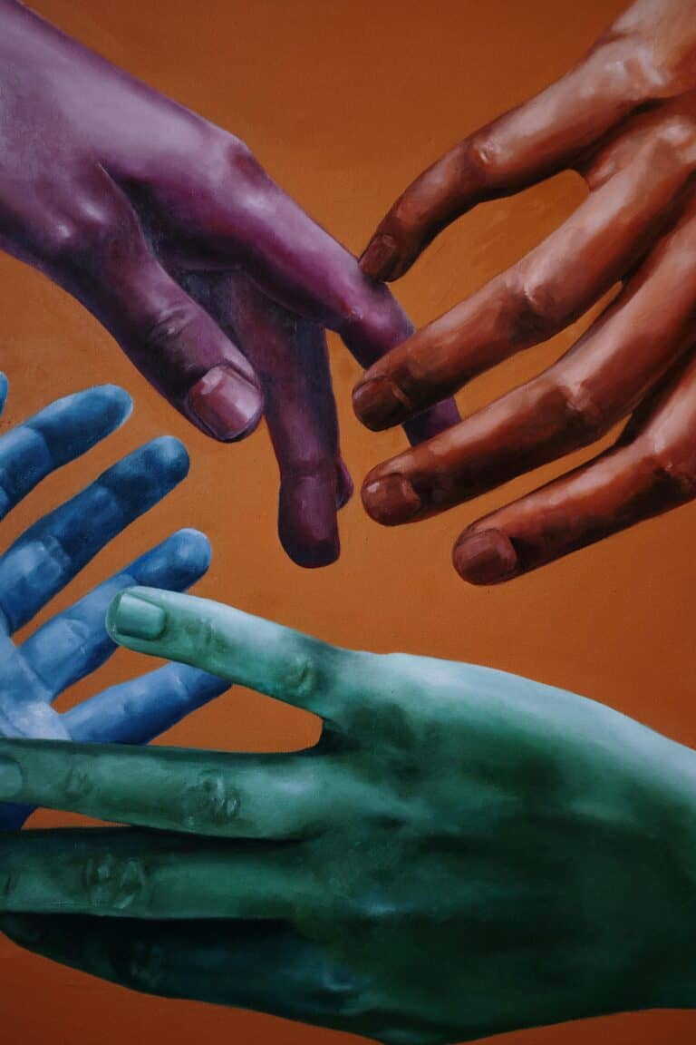 Cuatro manos pintadas de colores que se acercan unas a otras sobre un fondo naranja