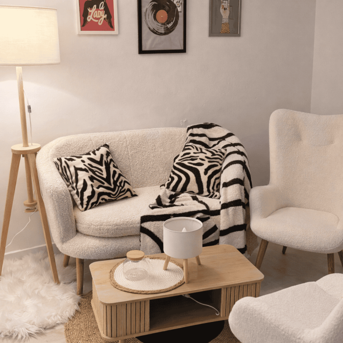 Sofá blanco con cojines y manta de rayas en sala moderna y acogedora.